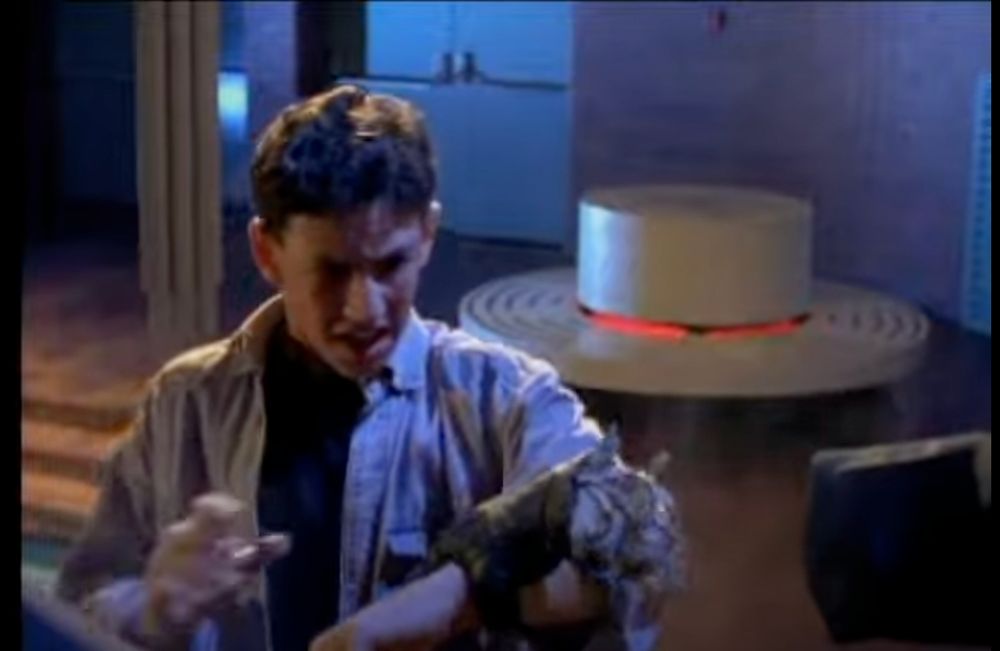 Ross stares in disgust at the disembodied hand of the enemies, still clutched to his arm. Behind him, a circular white bench with red lights in the middle can be seen, mimicking the bumpers of a pinball machine. 