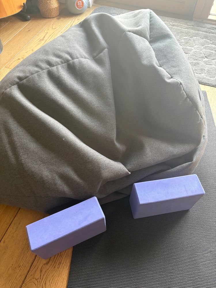 Squashed beanbag used as a chair normally, but as a prop for splits today, with two purple yoga blocks in front of it