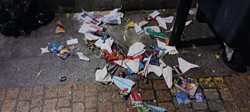 A pile of paper planes on the pavement at night