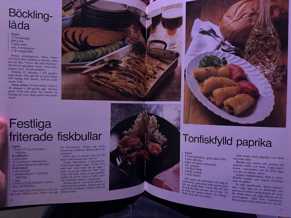 Ett uppslag i kokbok med tre rätter: en böcklinglåda med bröd och gurka, friterade fiskbullar med ris, och paprikahalvor fyllda med tonfisk serverade på fat.