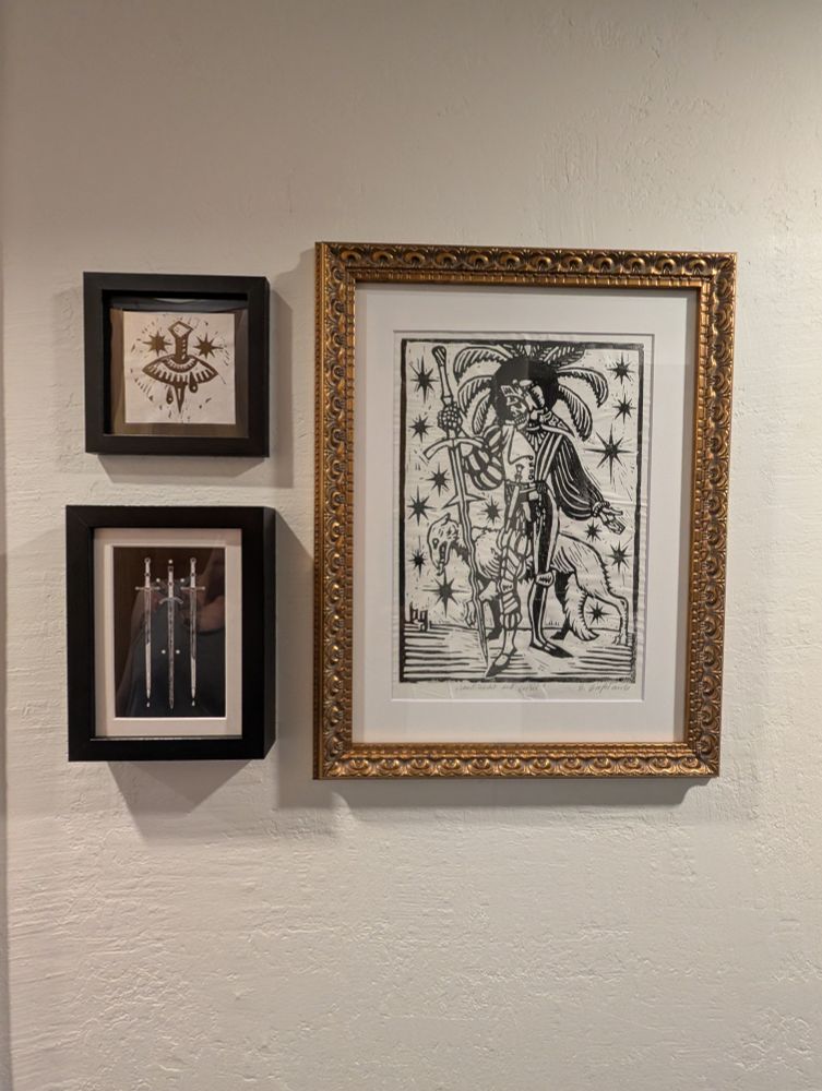 Framed dark fantasy print of swords and handmade block prints depicting skeleton knight with dog and eye symbol with dagger. 