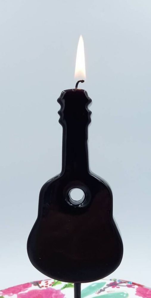 A candle shaped like an acoustic guitar ignited with a flame