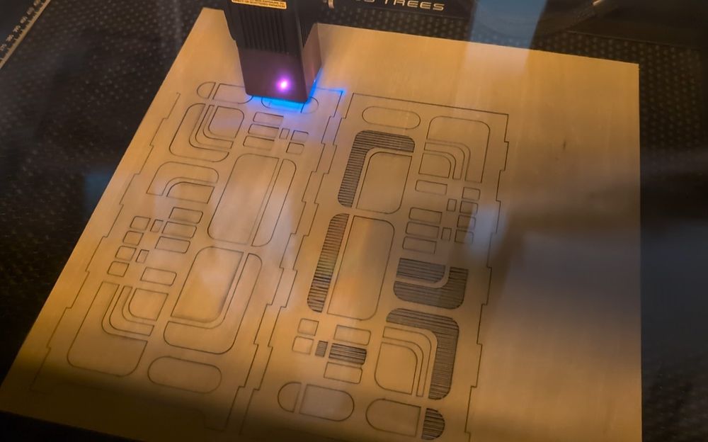 Diode laser cutter cutting out wood panels 