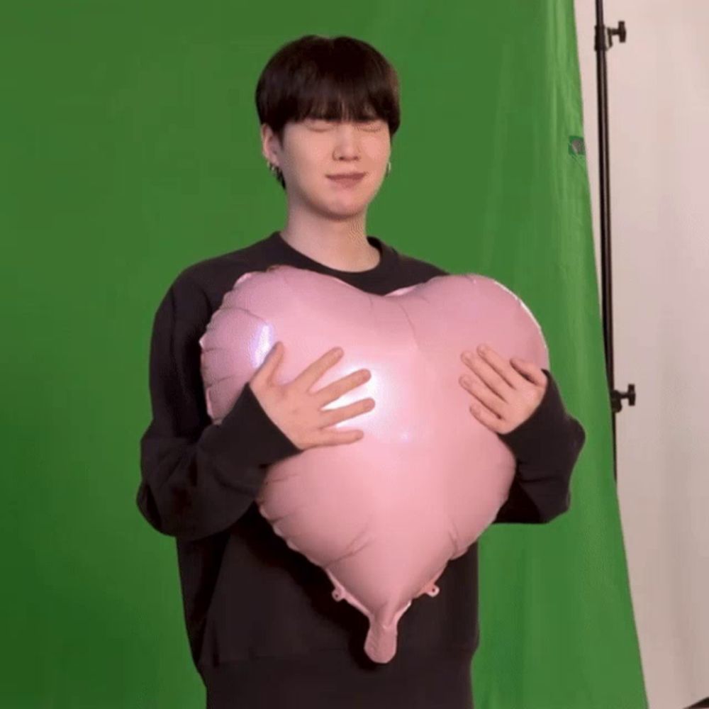 a man in a black sweater is holding a pink heart shaped balloon