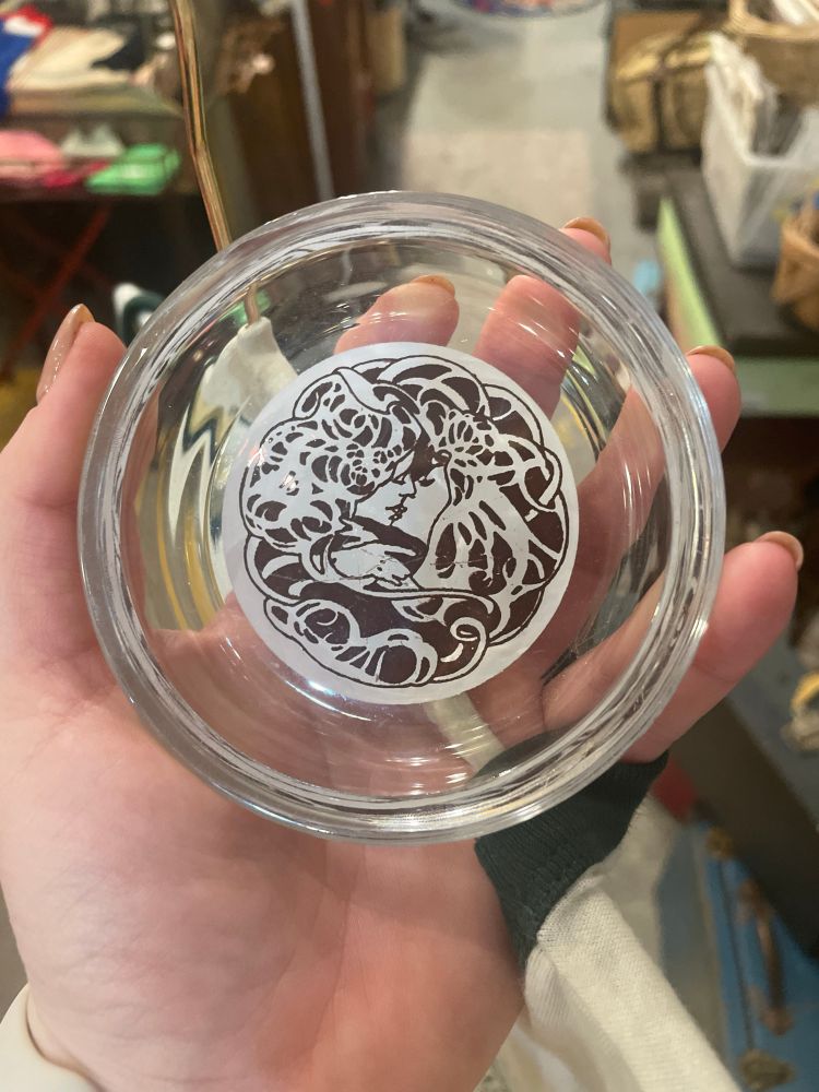 clear ash tray with a center circlet of two people kissing, akin to art nouveau style  