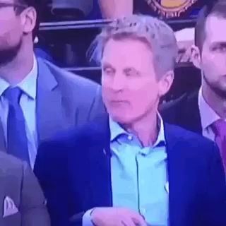a man in a suit and tie is sitting in a stadium .