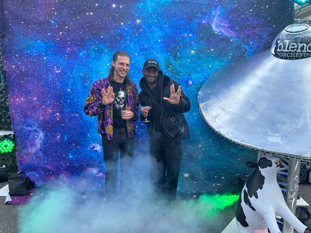 Jake and their friend Reggie are making Star Trek signs next to a space ship. There is a starry background and fog around them. 