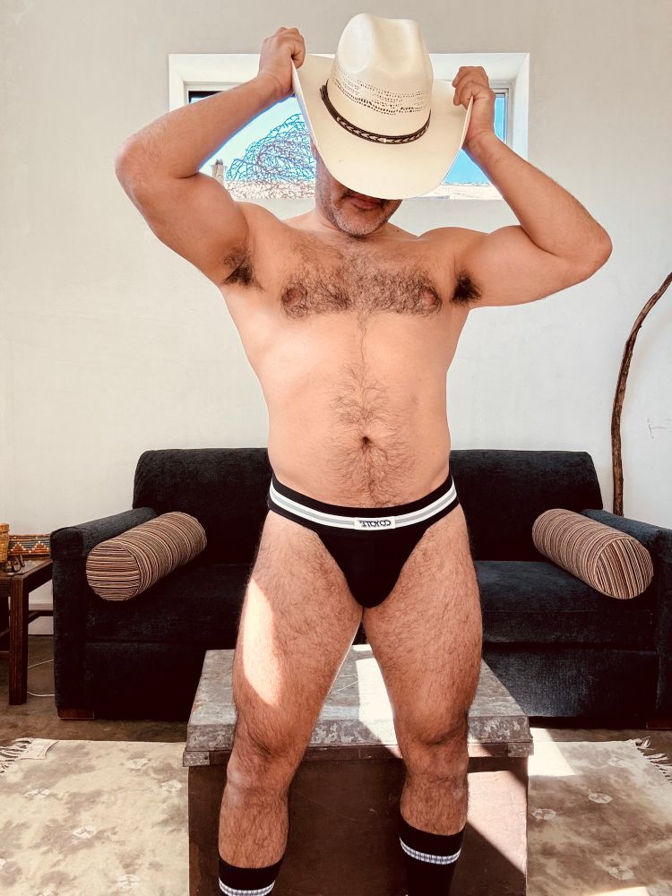 Wearing a cowboy hat covering face. Wearing black jockstrap and black socks with white stripes
