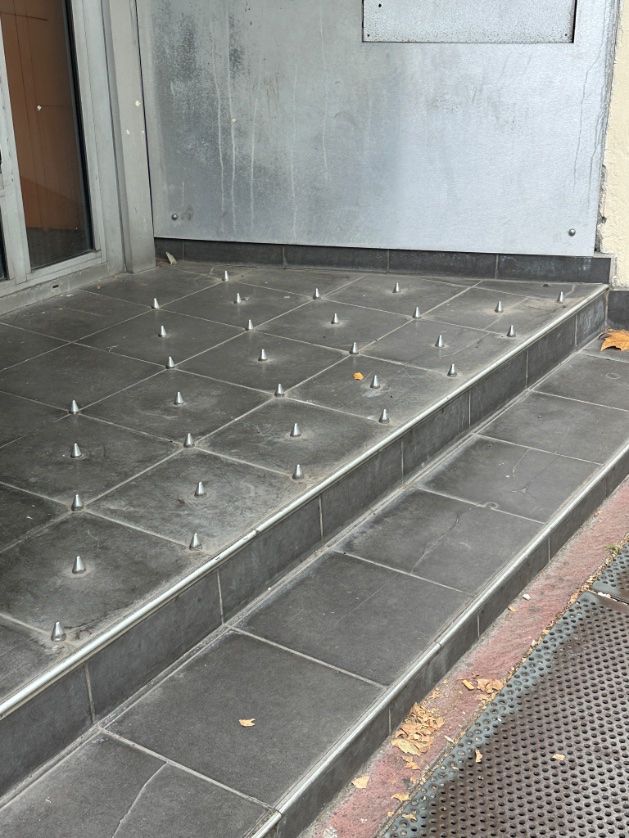 An enclave along a sidewalk with rows of small studs fixed to the ground