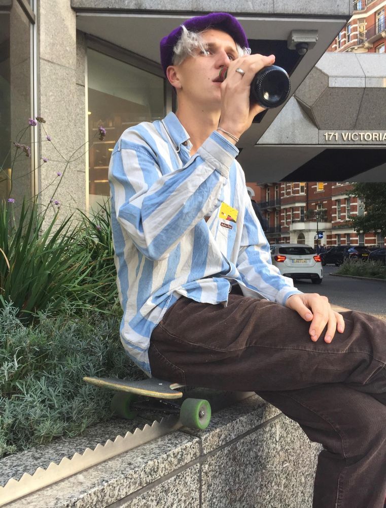 A skateboarder using their bird to sit atop a strip of metal spikes on a marble wall