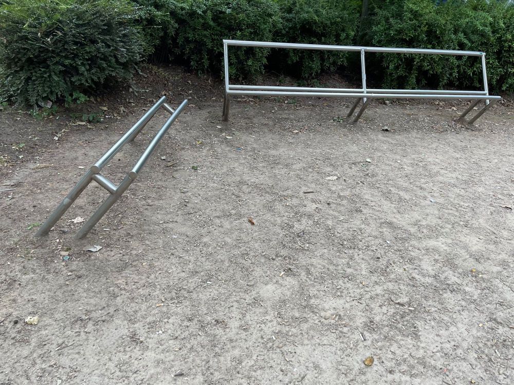 Two “benches” made of unpainted steel tubes with no actual seat on one and no back or seat on the other