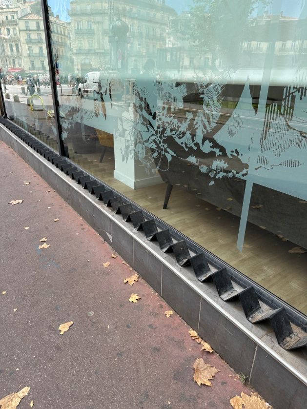 A small ledge along a window sill with metal triangles running along the surface