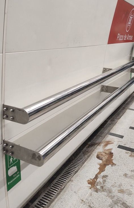 Two metal bars attached to a wall serving as a “leaning bench”