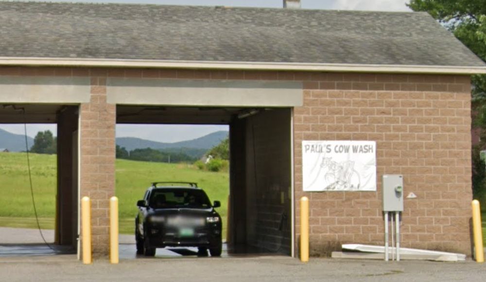 A self-service car wash with a sign that reads "Paul's Cow Wash"