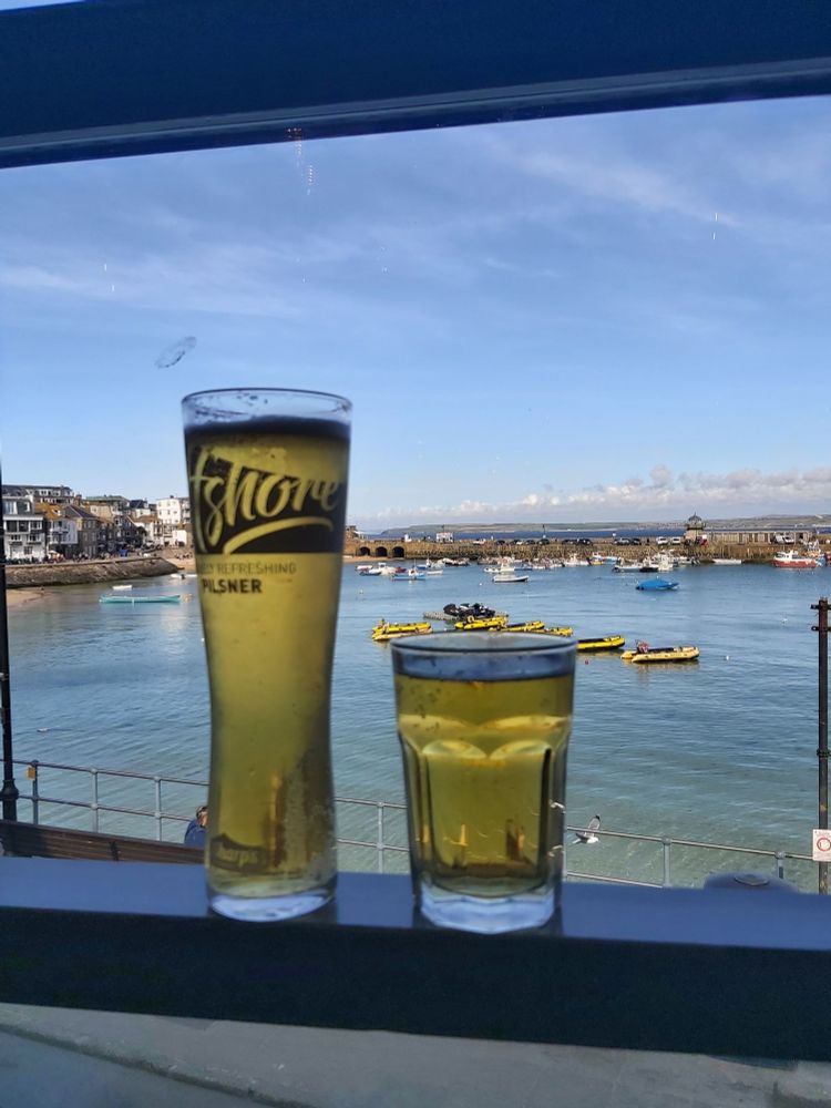 2 beers on a table, with St Ives harbour in the background. 