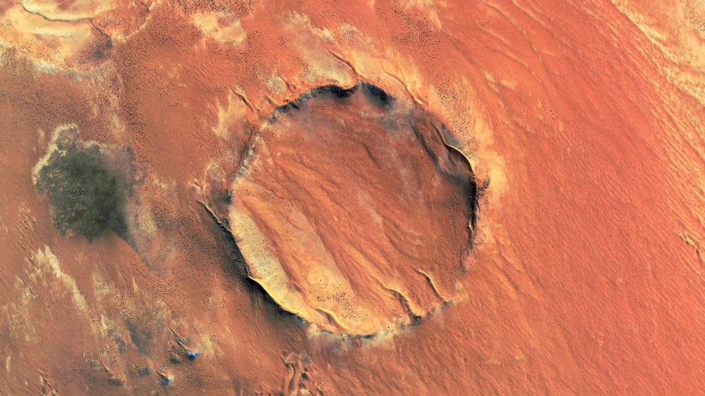 Roter Kamm crater - Namibia
a cicrcular red/orange crater in the middle of an red/orange desert, seen from above