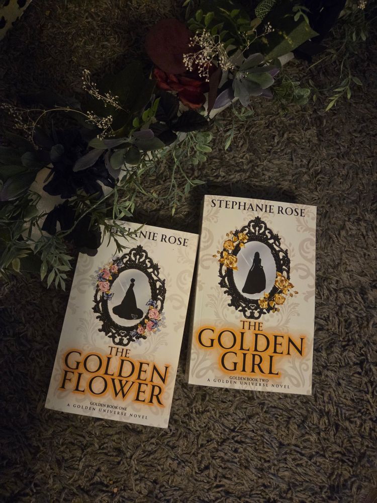 Picture of two books - The Golden Flower & The Golden Girl, by Stephanie Rose - with dark flowers and leaves overhead