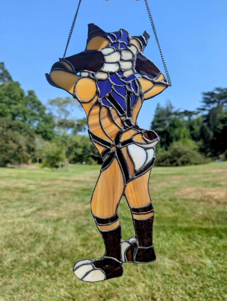Stained glass piece of a spacelynx fursuiter with his paws on the back of his head and showing off his impeccable butt