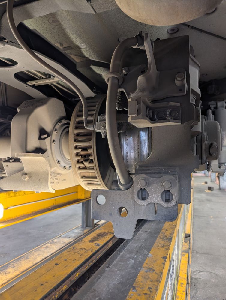 Eine Straßenbahn von unten, zu sehen ist ein Teil eines Drehgestells mit Radsatz und Scheibenbremse