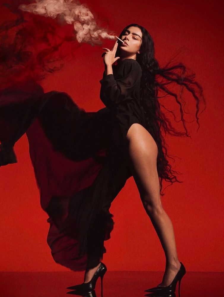 black dress with red background and smoke from a cigarette in her mouth 