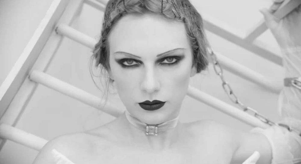 another close up of taylor on the bedframe. her right arm is chained and her hair is pinned up 