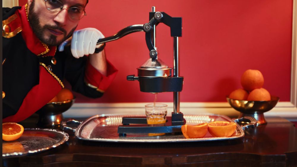 bbno$ squeezing oranges with a orange presser making orange juice. 