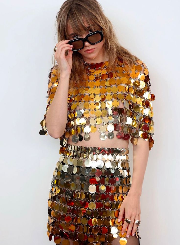 suki is taking her sunglasses off with her left hand and has her right hand resting on her leg. same outfit as previous pics 