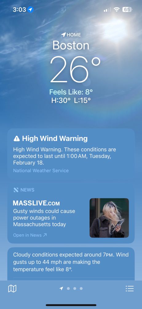 Weather app says temperature in Boston at 3:03 PM (15:03) is 26° Fahrenheit (-3.33° Celsius), feeling like 8° Fahrenheit (-13.3° Celsius) because of high winds (up to 44 MPH/70.8 KPH) that are expected to last until 1:00 AM the next day. High is 30° Fahrenheit (-1.11° Celsius), low is 15° Fahrenheit (-9.44° Celsius), and cloudy conditions are expected around 7:00 PM (18:00). An advertisement in the middle of the screen says that “Gusty winds could cause power outages in Massachusetts today.”