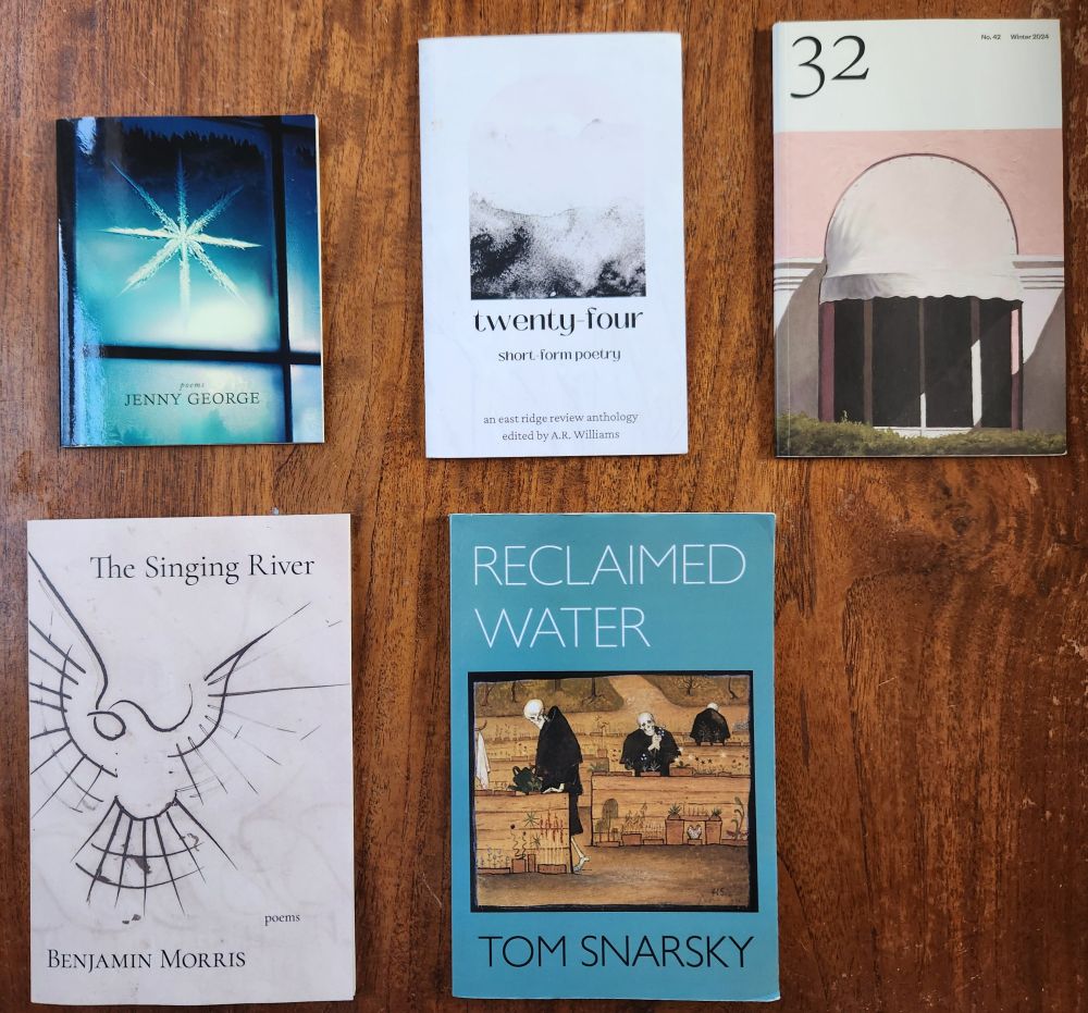 five books, arranged on a wooden table: asterisk by Jenny George, twenty-four: short form poetry, edited by A.R. Williams, The Singing River by Benjamin Morris, Reclaimed Water by Tom Snarsky, and 32 poems - winter 2024 issue.