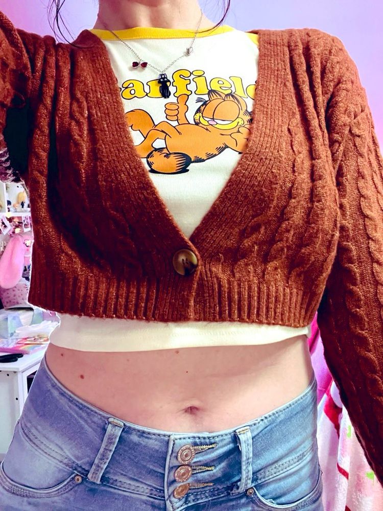 selfie of my fit for Round1, I’m wearing my Jiji necklace from Himi, a raglan tee with yellow sleeves and a white front featuring Garfield, a burnt orange buttoned sweater, and blue jeans