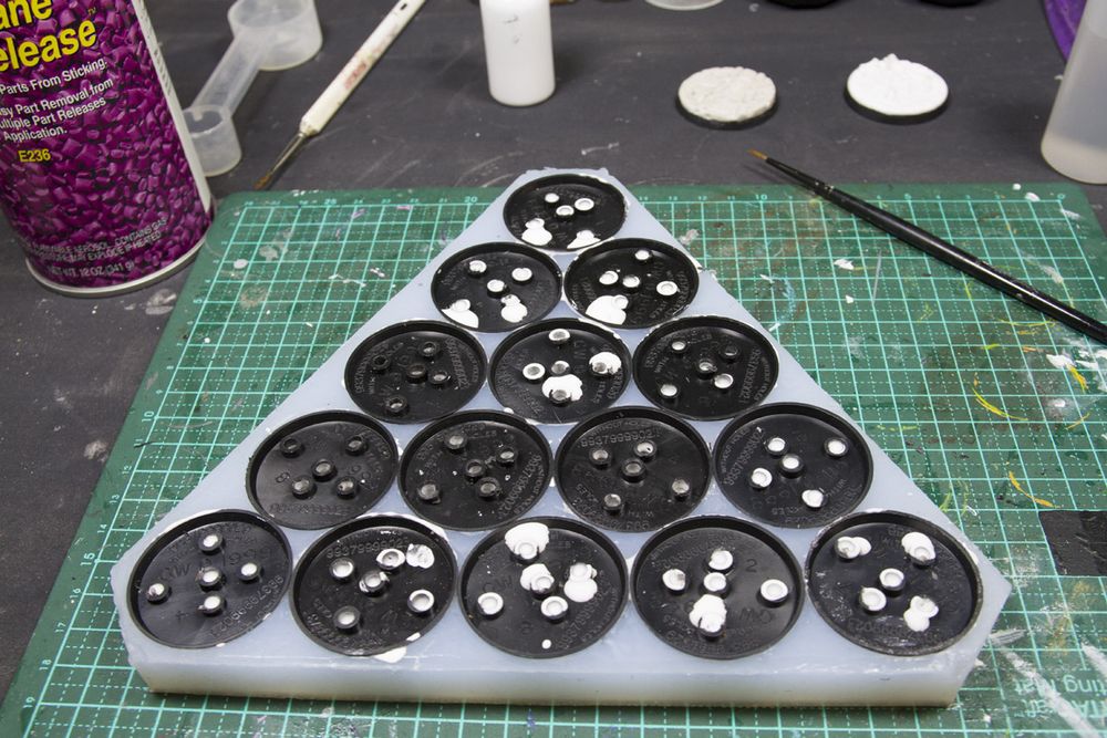 Bases in a mold. Excess resin goes through the holes in the bases and comes out the other side.