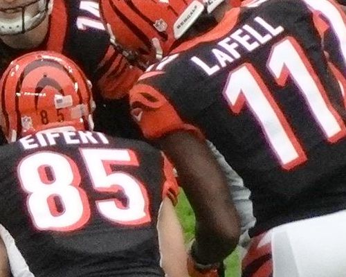 Photo of backs of football player uniforms with last names and numbers in large print.