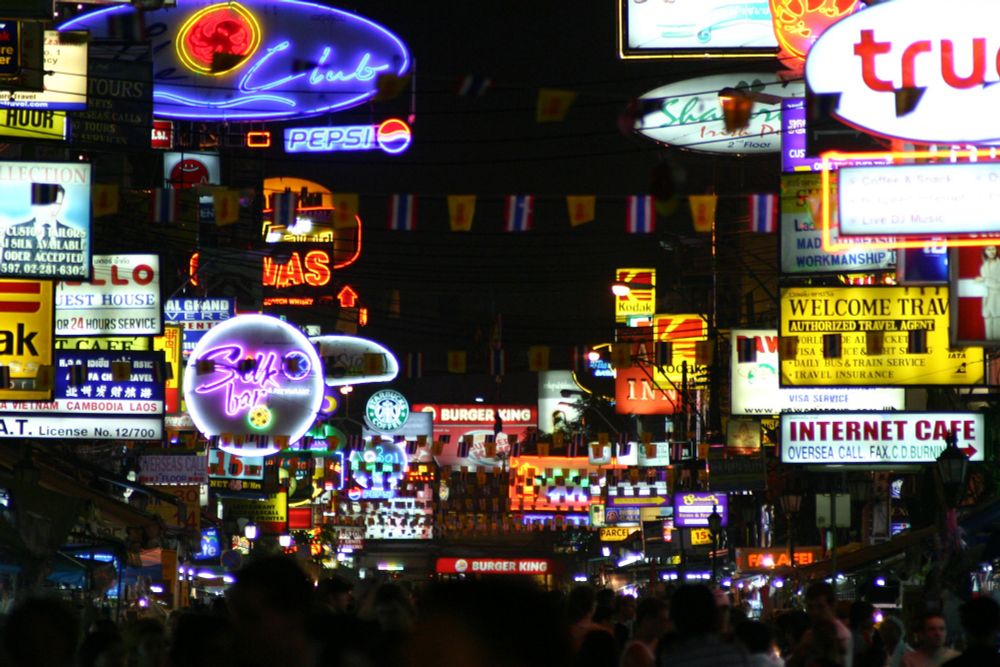 Viele Schilder und Leuchtreklame über einer Straße mit vielen Menschen. (2005)