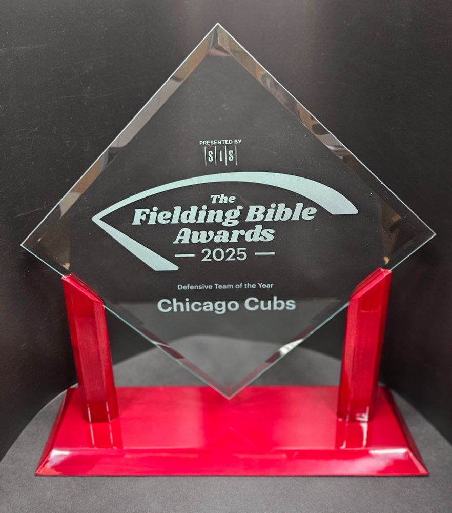 A glass trophy on a red base with the words "The Fielding Bible Awards 2025- Presented by SIS - Defensive Team of the Year: Chicago Cubs" engraved in the glass.