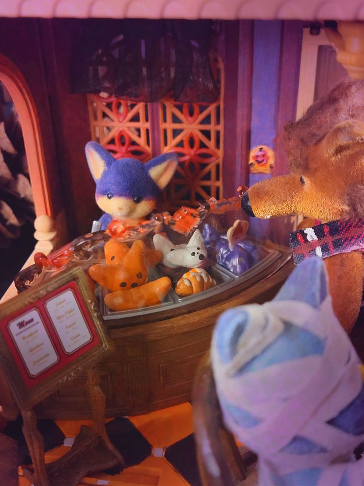 A bat mans the counter, serving up a ton of little spooky pastries and mysterious purple shimmery goop.