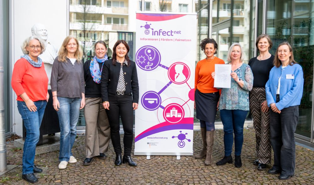 Gruppenfoto der Gründungsmitglieder des Verbands Deutscher Infektionsforscherinnen - Infect-Net. Acht lächelnde Frauen stehen um ein Werbebanner des Frauennetzwerks Infect-Net. Eine Frau hält die unterschriebene Satzung in die Kamera. Foto: Kathrin Czoppelt.