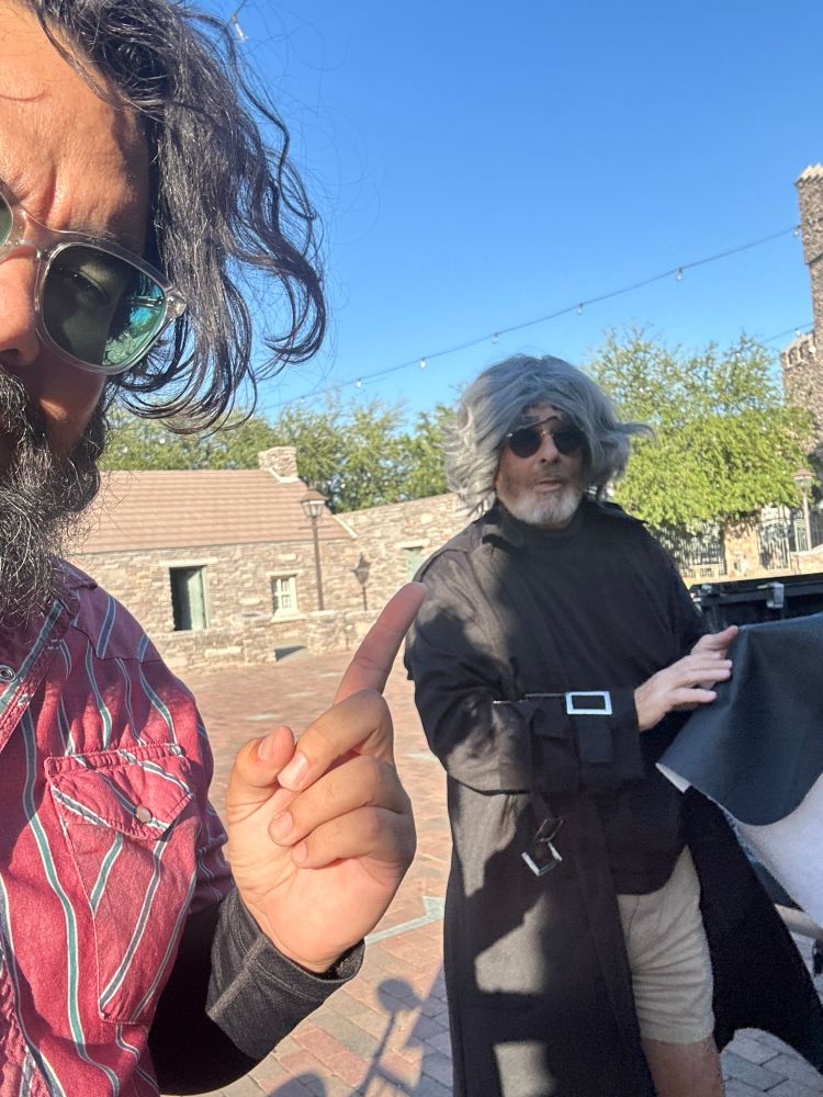 Yrs, a beautiful brown beardo, pointing at a guy who looks like a Klingon John Lennon in a robe and khaki shorts.