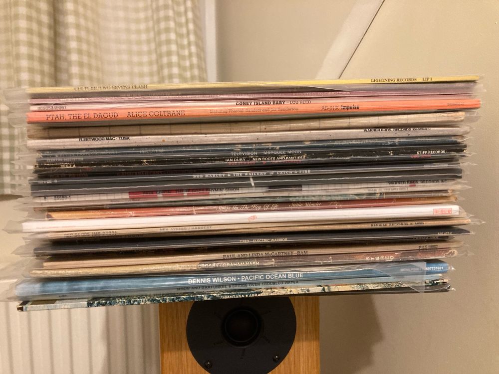 A pile of records from the 70s perched precariously on top of a speaker