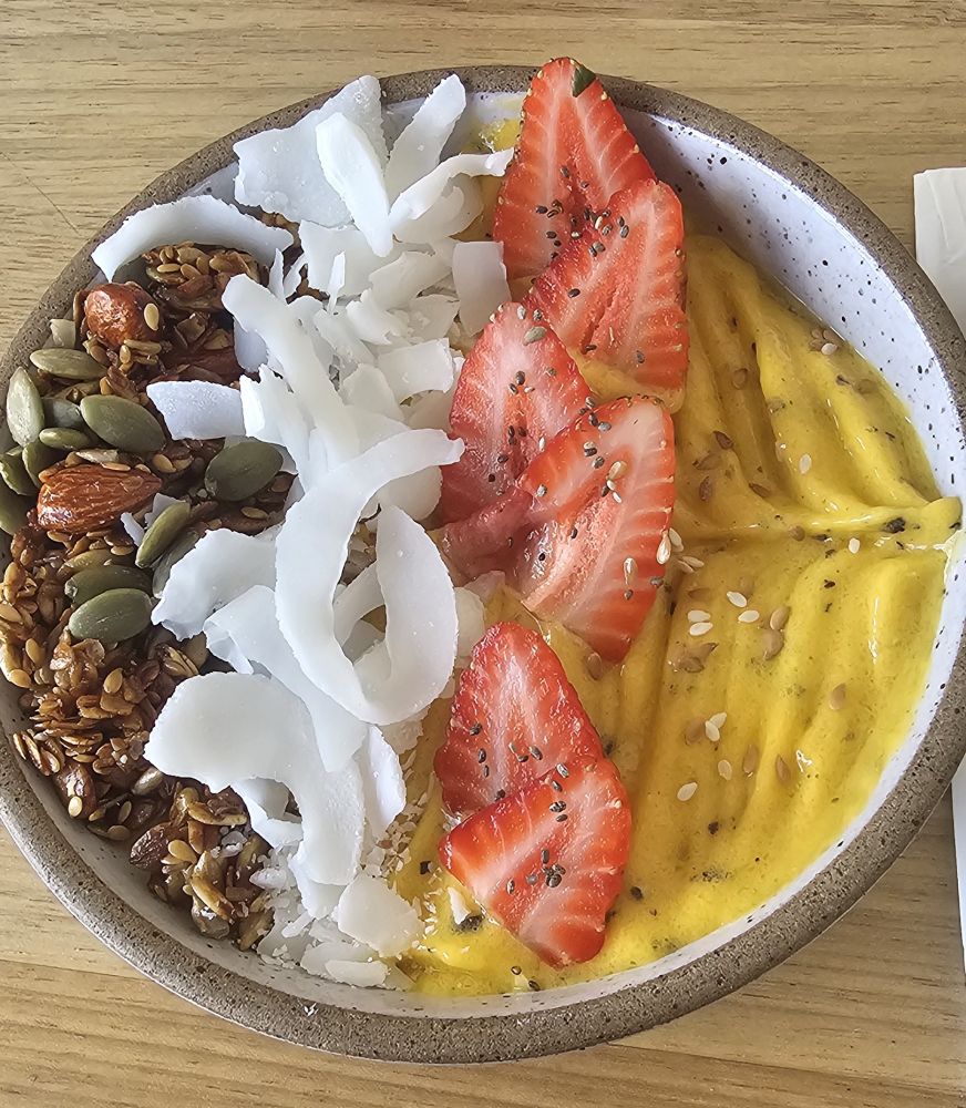 Foto de um bowl com creme de maracuja, morangos picados, lasca de coco e granola