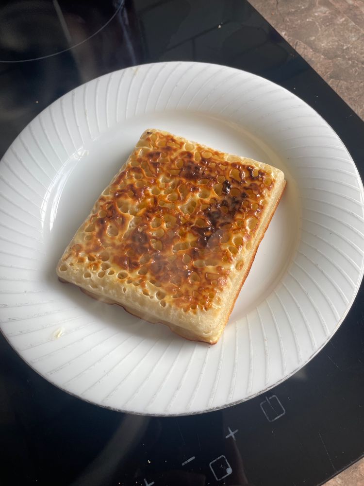 A toasted and buttered rectangular crumpet on a plate