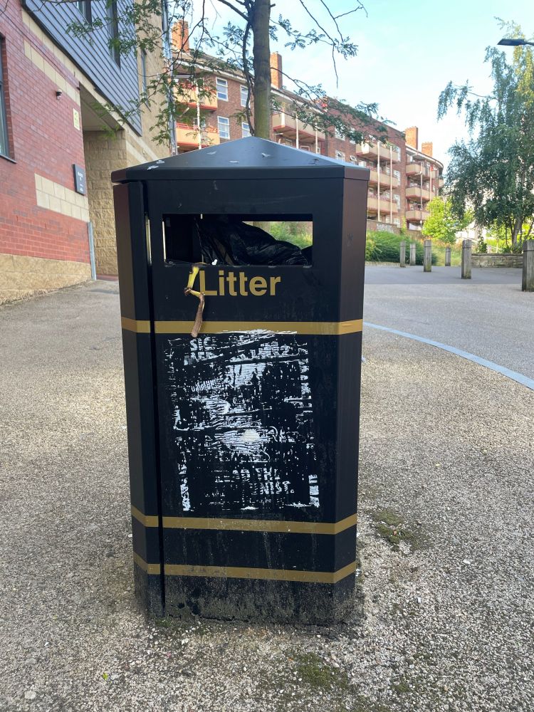 A photo of a litter bin with the residue of a poster on it