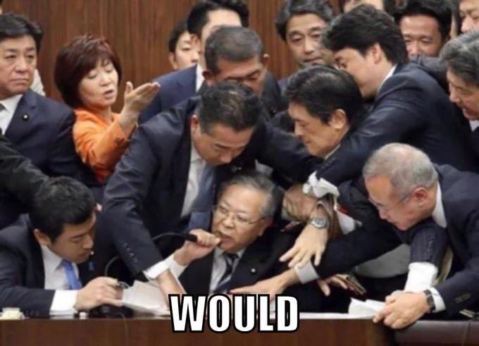 A chaotic scene in what appears to be a government meeting, with multiple individuals aggressively crowding around one seated man holding a microphone. The image has the word ‘WOULD’ boldly captioned at the bottom.