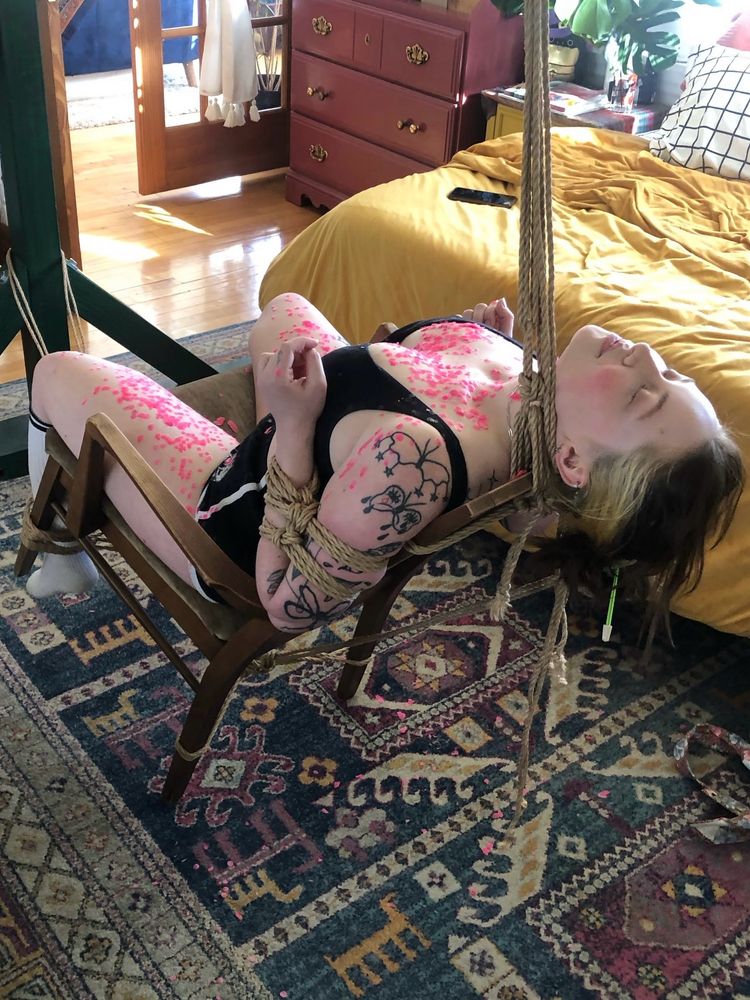 tied to a chair and covered in pink wax