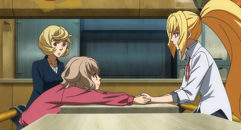 a screenshot from Mobile Suit Gundam: Iron-Blooded Orphans showing Atra leaning all the way across the table so she can clasp her hands around Kudelia's, who's looking at her in surprise