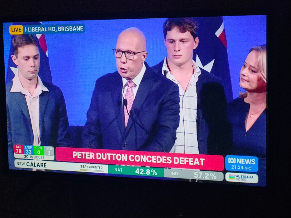 Peter Dutton conceding defeat behind a banner saying Peter Dutton Concedes Defeat