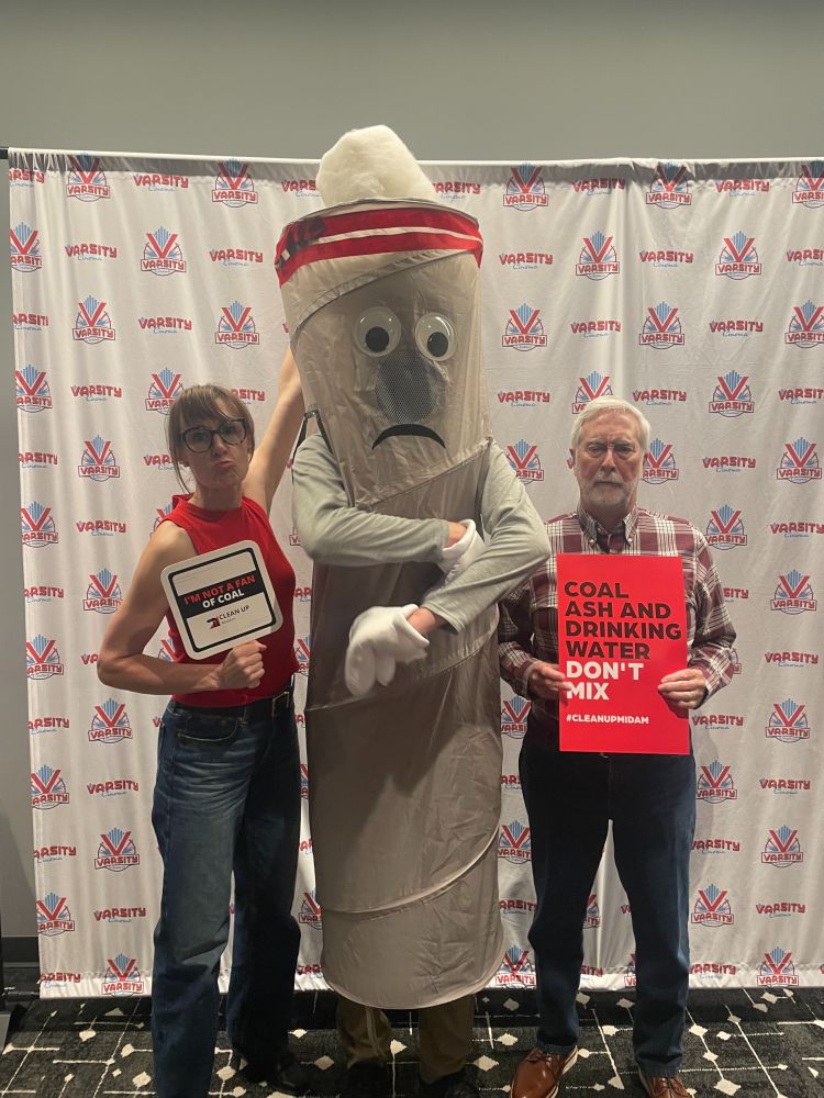 Two adults frowning while posting with a human dressed as a coal stack. 