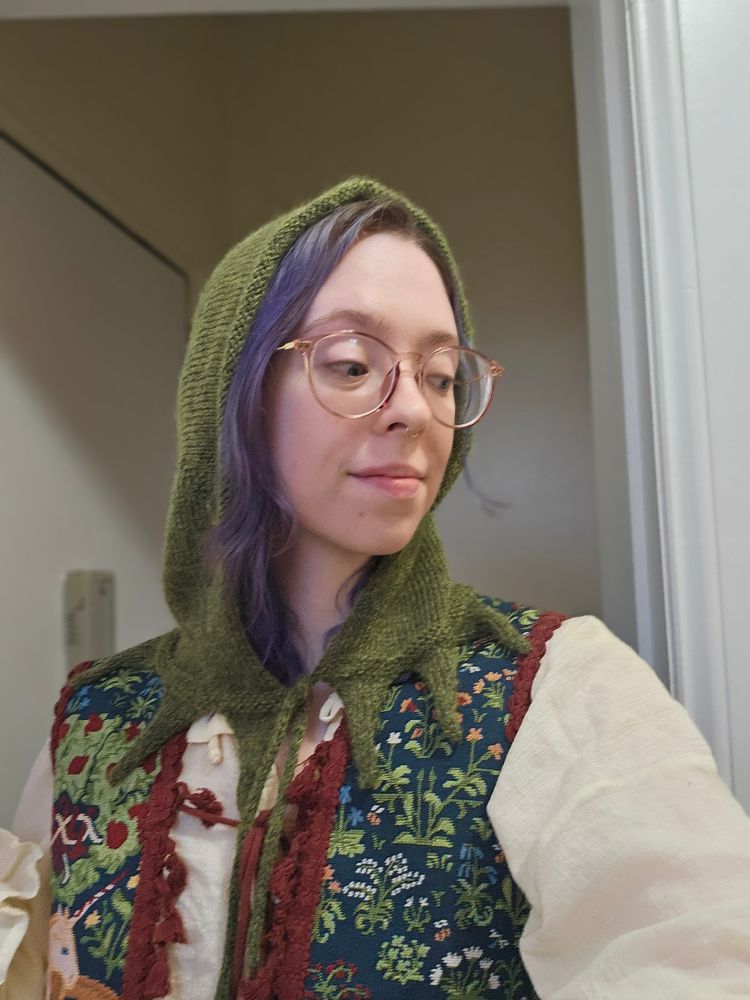 The same person in a knitted Kermit hood, but from the side 
