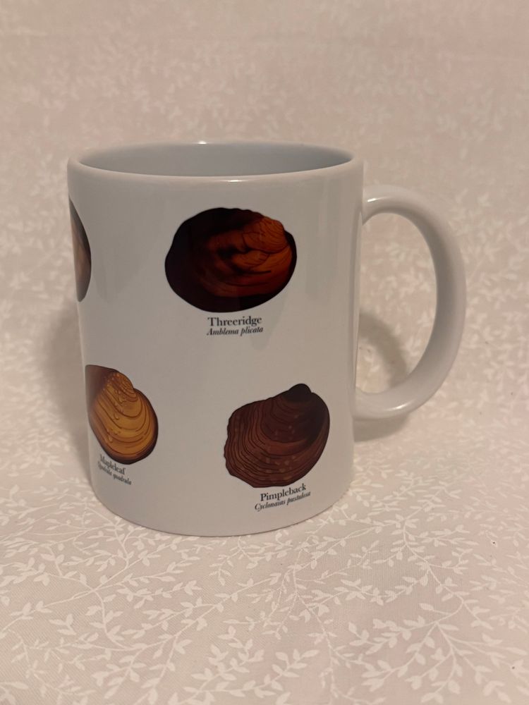 A white ceramic mug with illustrations of a threeridge, mapleleaf, and pimpleback