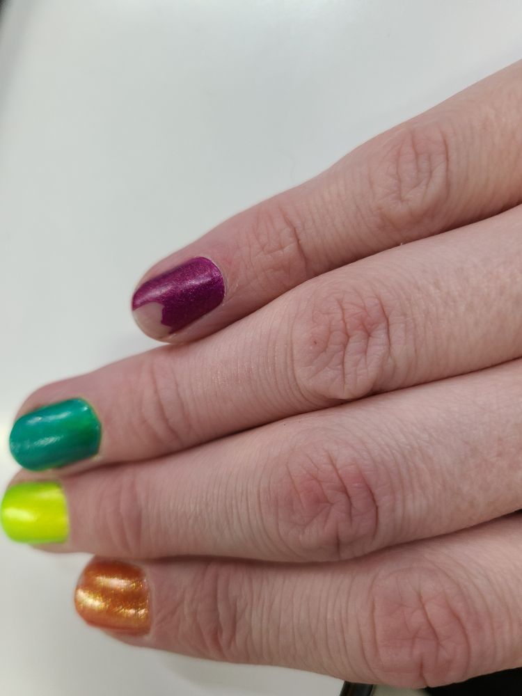 Painted fingernails with the purple pinkie having already chipped significantly 