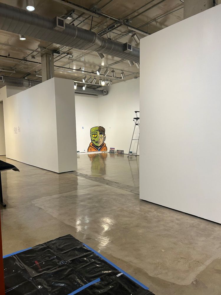 A gallery being installed with a split image of a boy / lizard boy being installed from the xover of the graphic novel Tales of a Seventh-Grade Lizard Boy. 